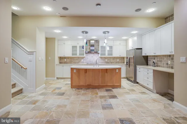a large kitchen with kitchen island a stove a sink a counter top space and cabinets
