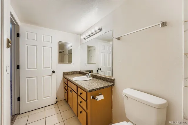 a spacious bathroom with a granite countertop sink mirror vanity and toilet