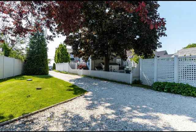 a view of a house with a big yard and potted plants and large trees