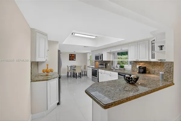 a kitchen with granite countertop a sink stainless steel appliances and white cabinets