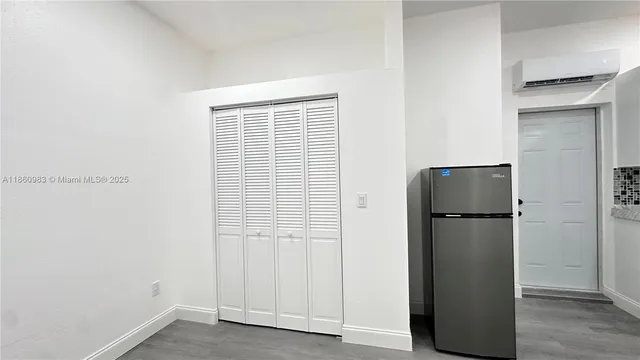 a room with a refrigerator and wooden floor