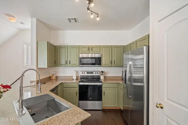 a kitchen with stainless steel appliances granite countertop a stove a sink and a refrigerator