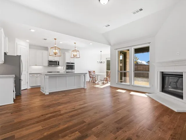 a kitchen with stainless steel appliances granite countertop a sink a stove a refrigerator cabinets and wooden floor