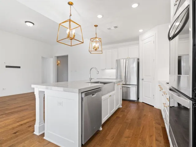 a kitchen with stainless steel appliances a dining table chairs refrigerator and microwave