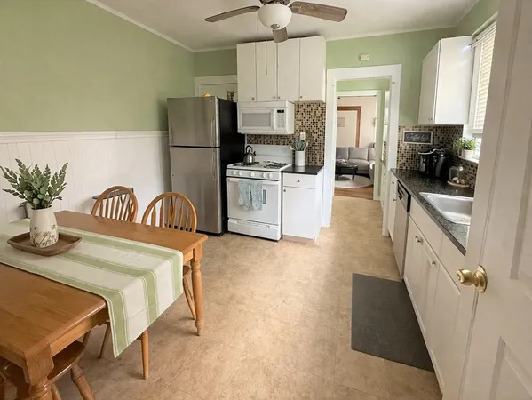 a kitchen with granite countertop white cabinets and refrigerator