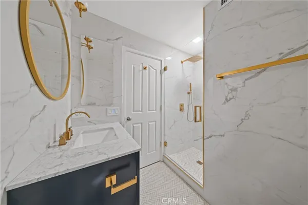 a bathroom with a granite countertop sink a mirror a vanity and shower