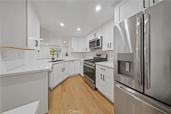 a kitchen with white cabinets stainless steel appliances and sink