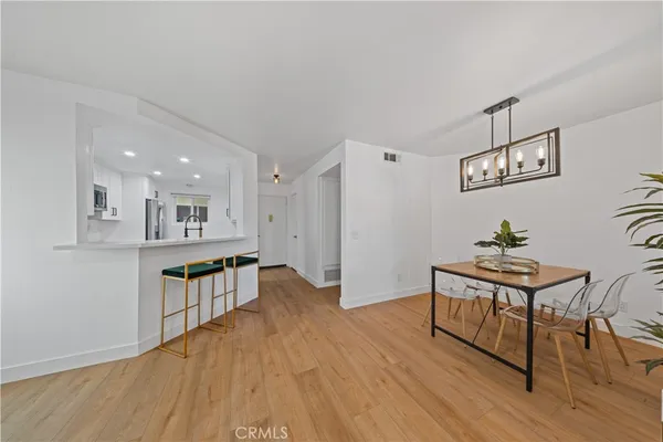 a living room with kitchen island a wooden floor and a dining table