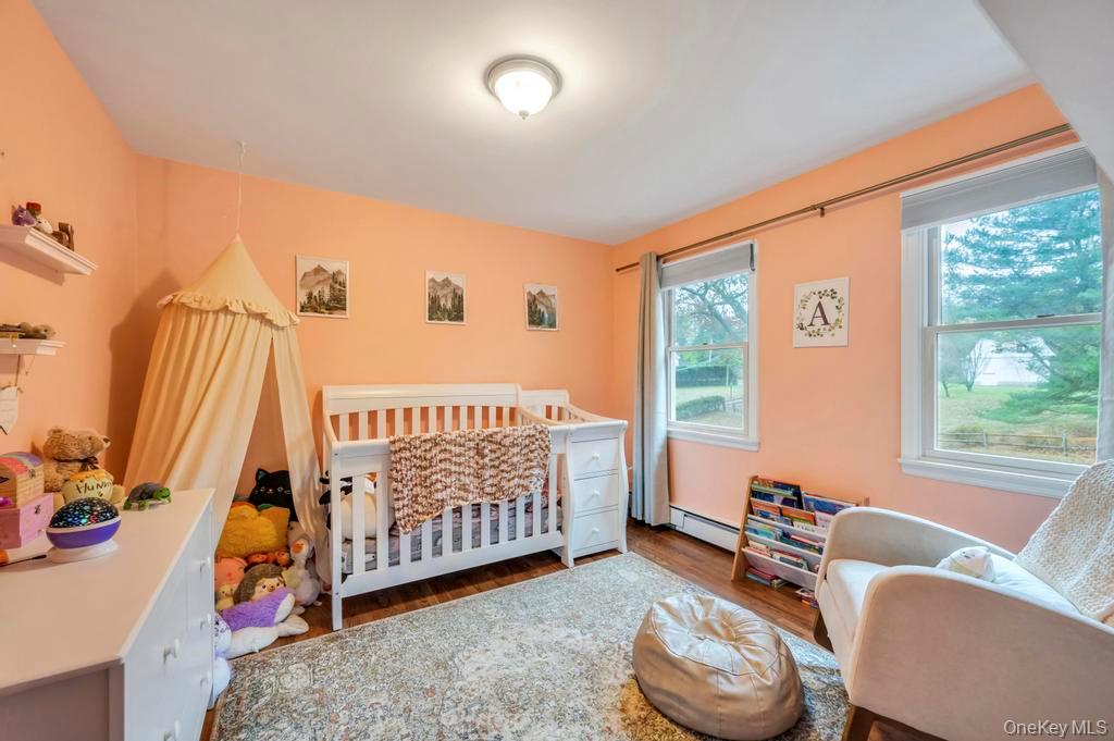 39 Bevin Road Northport, NY 11768 - Photo 25 of 44 Bedroom with a crib, wood finished floors, and baseboard heating