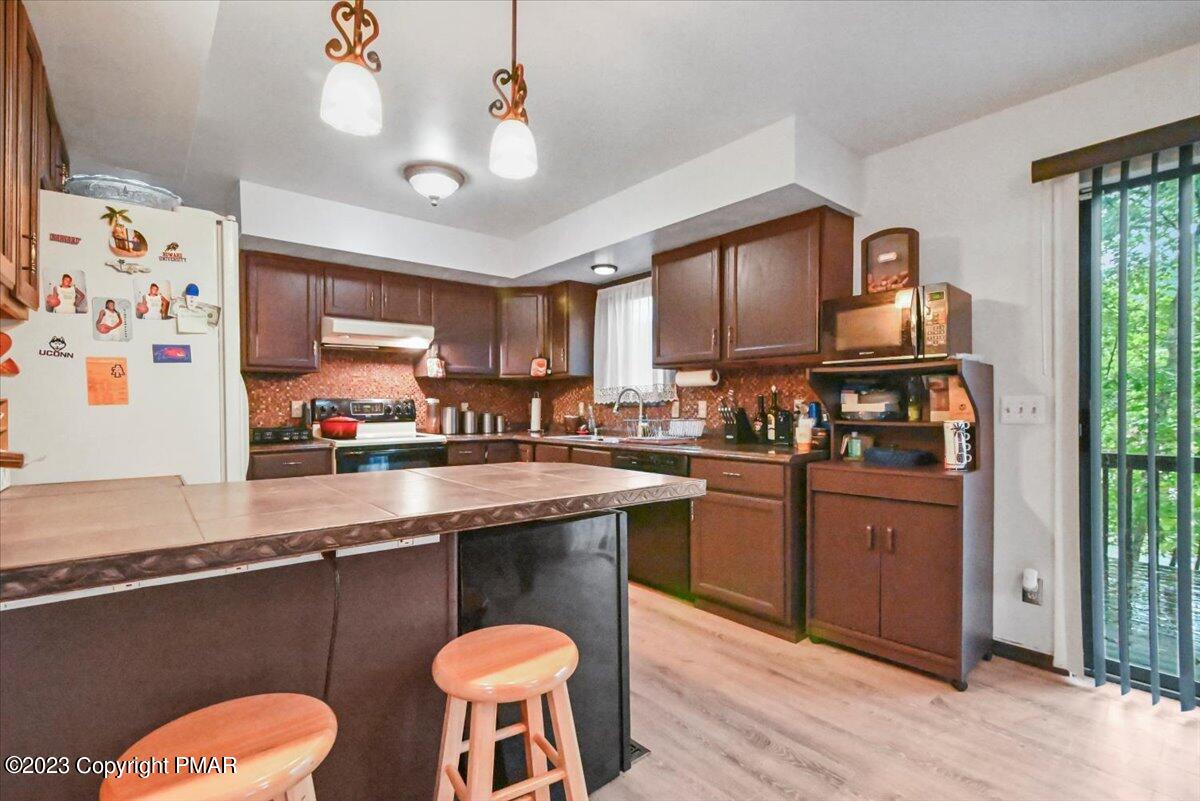 3237 Windemere Drive Bushkill, PA 18324 - Photo 9 of 50 a kitchen with stainless steel appliances granite countertop a stove a sink dishwasher and a refrigerator with wooden cabinets
