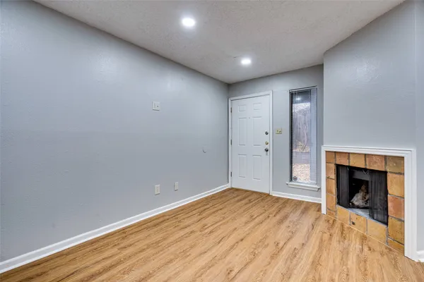 a view of empty room with wooden floor and fireplace