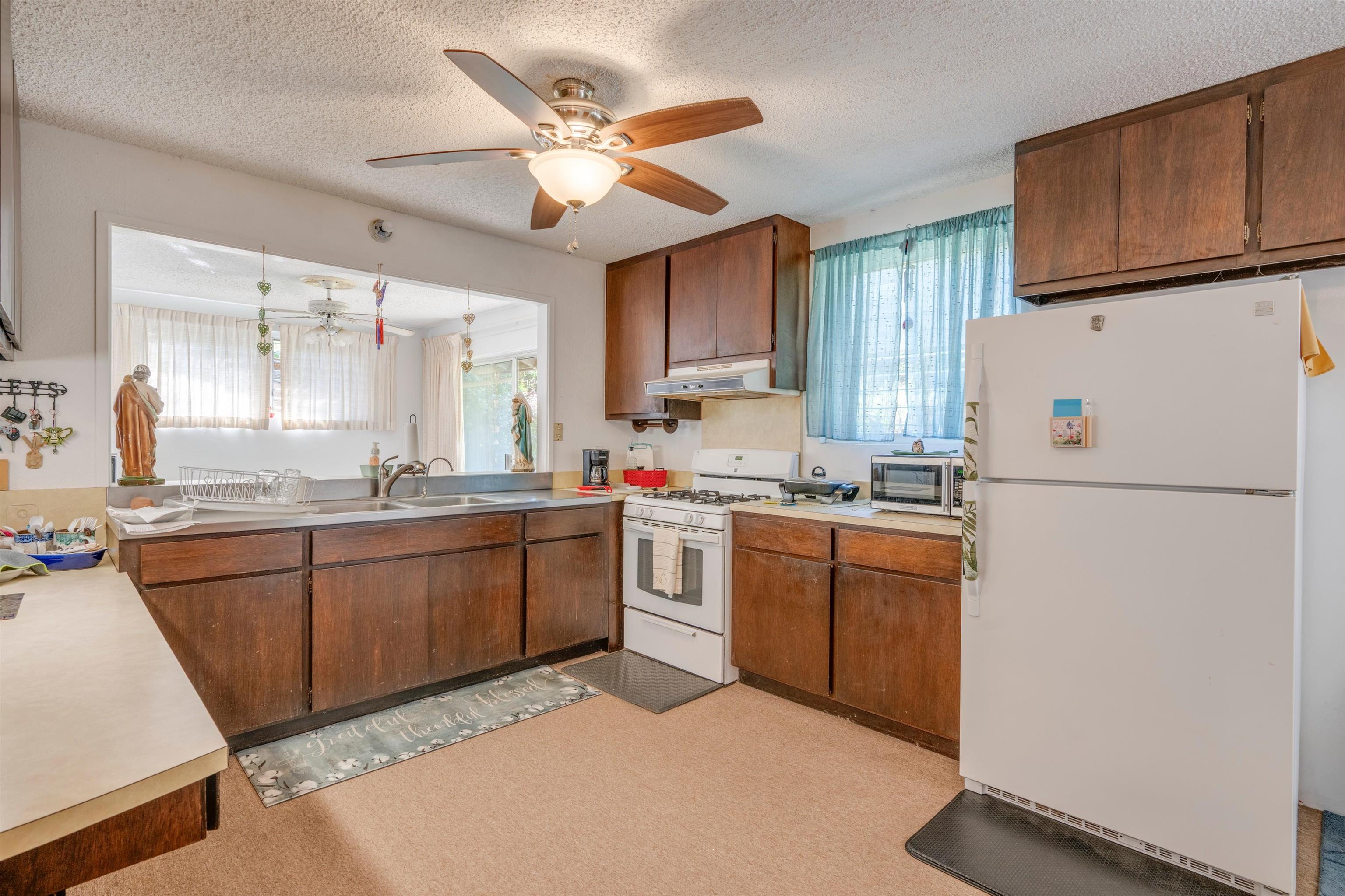 2475 Kaupakalua Road Haiku, HI 96708 - Photo 7 of 28 a kitchen with sink a refrigerator and wooden cabinets
