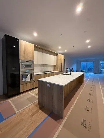 a large kitchen with stainless steel appliances kitchen island a large counter top a refrigerator and a sink