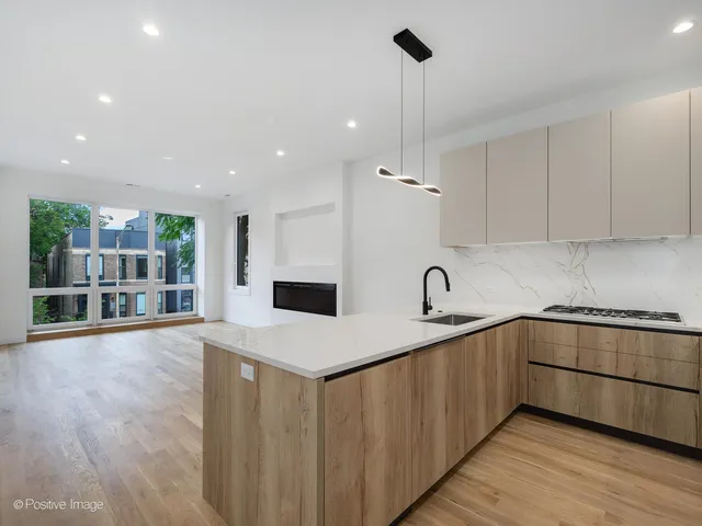 a kitchen with stainless steel appliances granite countertop a sink a stove and white cabinets with wooden floor