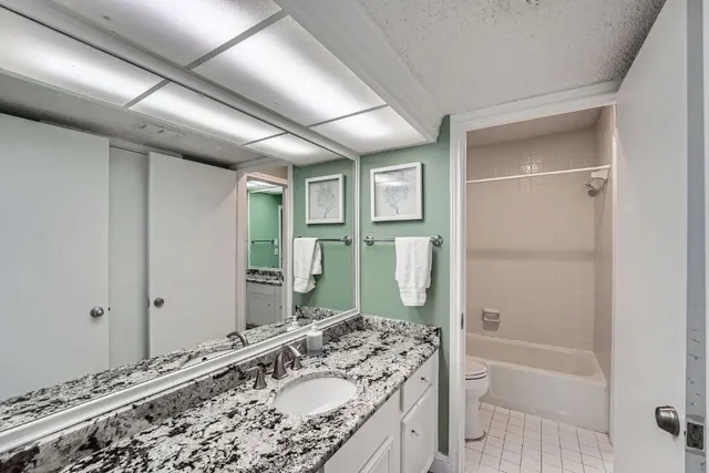 a bathroom with a granite countertop sink a mirror and a bathtub