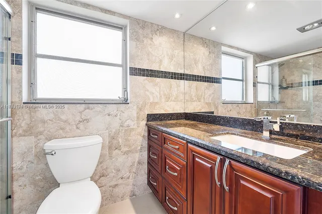 a bathroom with a granite countertop toilet sink and mirror