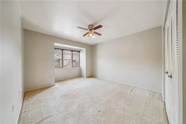an empty room with windows and ceiling fan