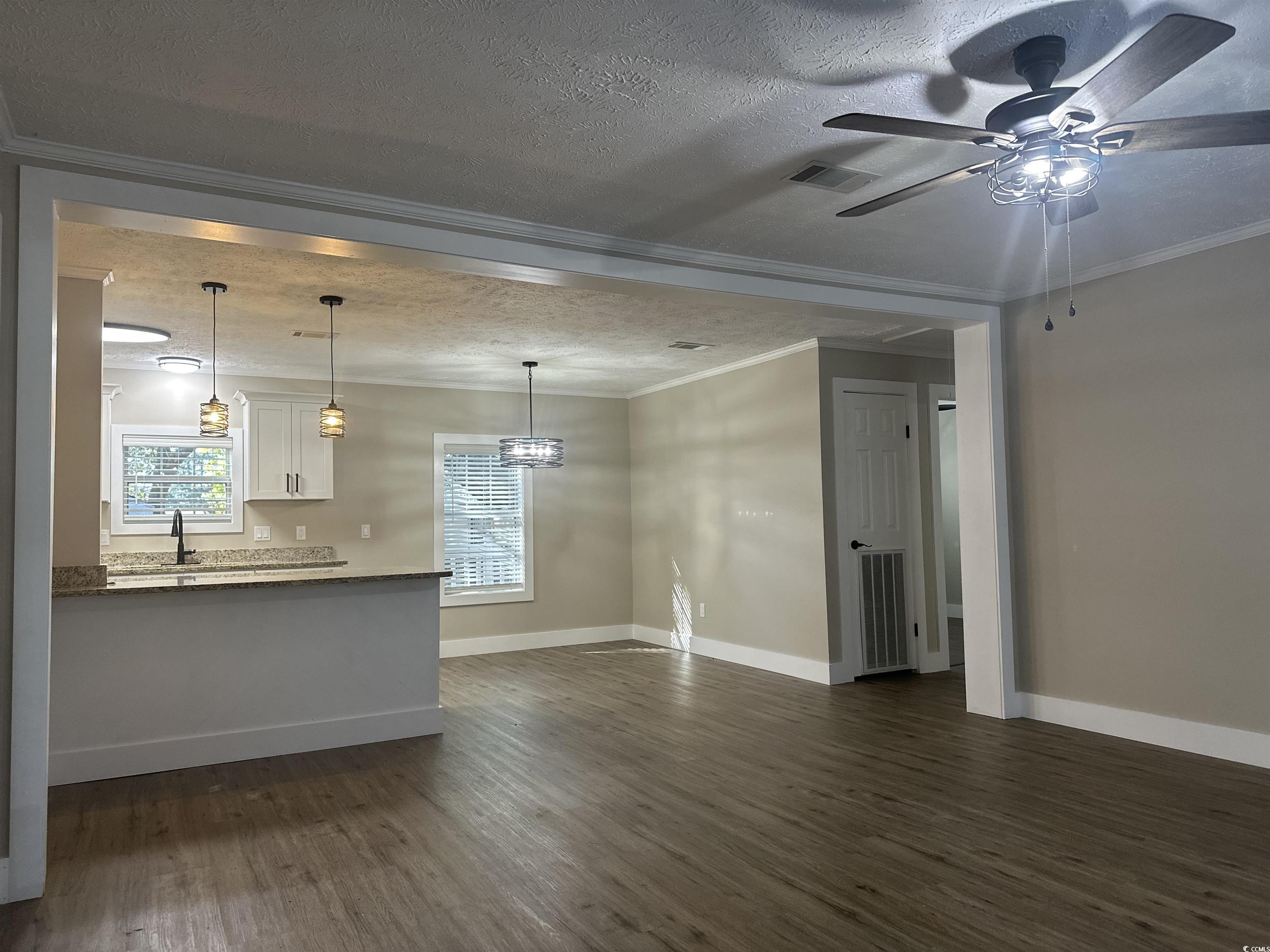 3800 Murrells Inlet Road Murrells Inlet, SC 29576 - Photo 19 of 22 Unfurnished living room featuring a textured ceiling, dark wood finished floors, ornamental molding, ceiling fan, and a chandelier