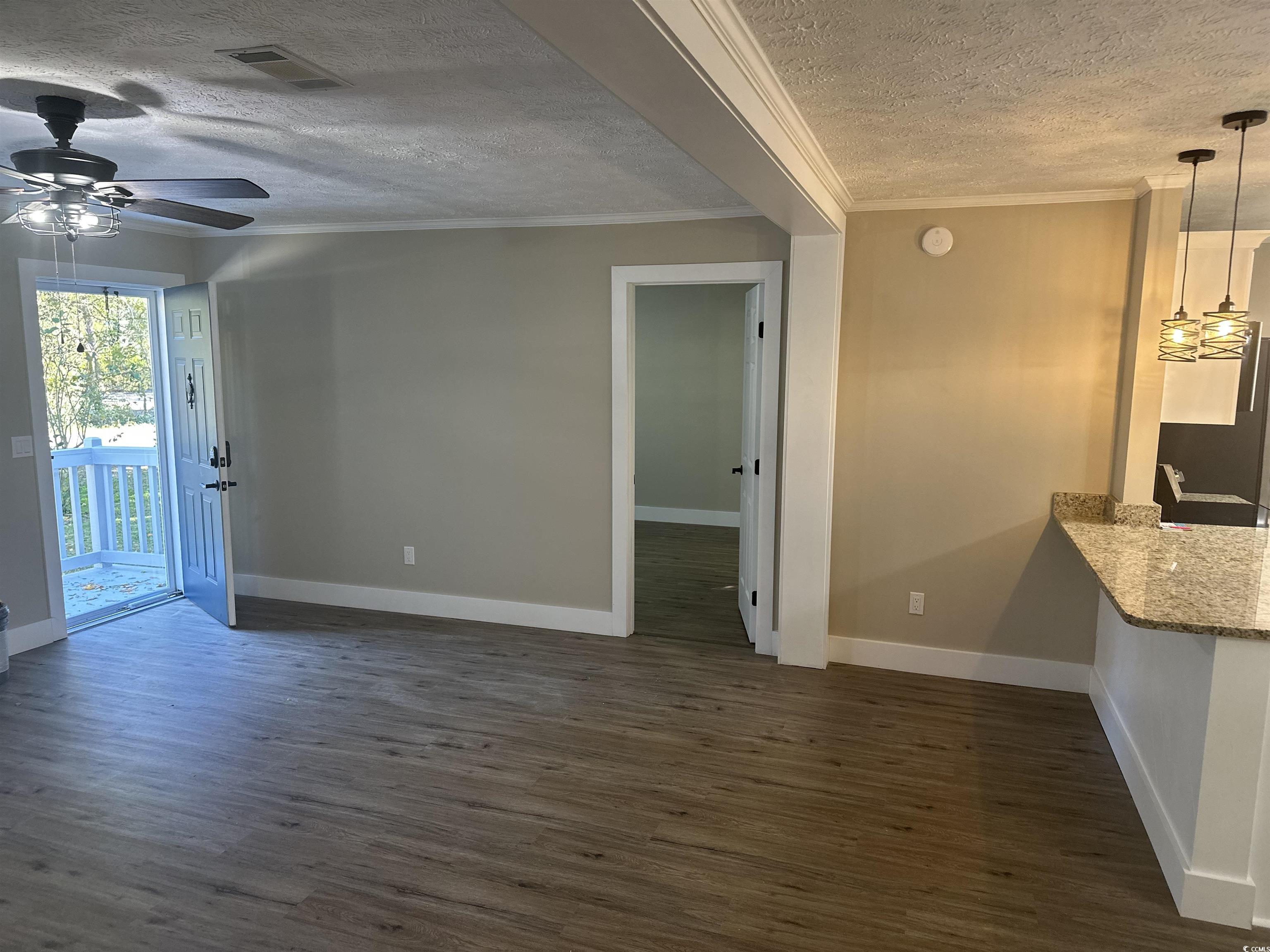3800 Murrells Inlet Road Murrells Inlet, SC 29576 - Photo 3 of 22 Unfurnished living room with a textured ceiling, dark wood-type flooring, crown molding, and a ceiling fan