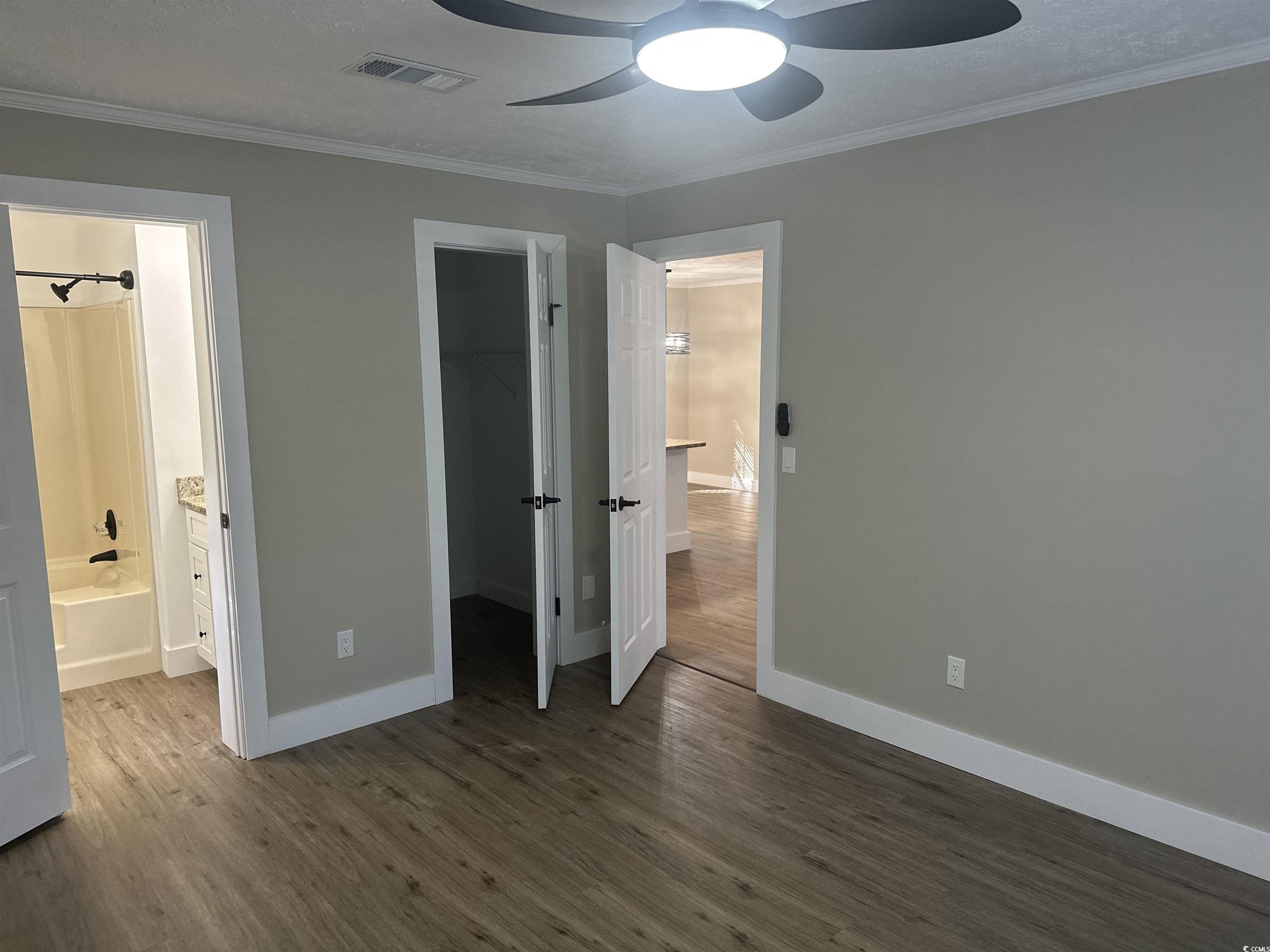 3800 Murrells Inlet Road Murrells Inlet, SC 29576 - Photo 8 of 22 Unfurnished bedroom with dark wood-style flooring, a spacious closet, crown molding, a ceiling fan, and ensuite bath