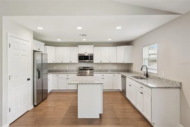 a kitchen with a sink stove cabinets and refrigerator
