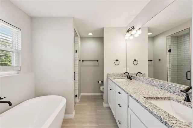 a spacious bathroom with a granite countertop sink a toilet a mirror and shower