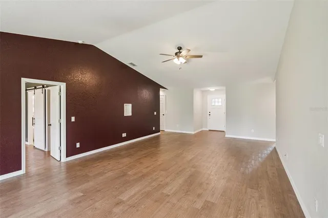 a view of empty room with wooden floor and ceiling fan