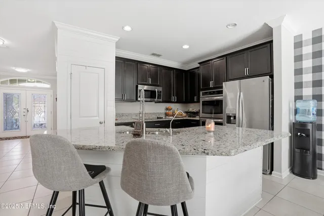 a kitchen with stainless steel appliances granite countertop a refrigerator a stove a sink a dining table and chairs