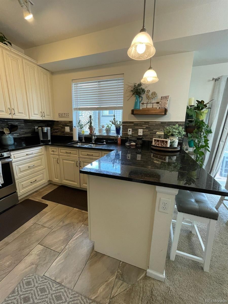 12948 Grant Circle East, Unit B Thornton, CO 80241 - Photo 13 of 24 a kitchen with stainless steel appliances granite countertop a stove a sink and a microwave