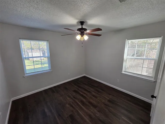 an empty room with a window and a ceiling fan