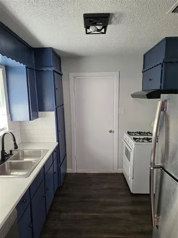 a kitchen with stainless steel appliances granite countertop a refrigerator a sink a stove and a refrigerator