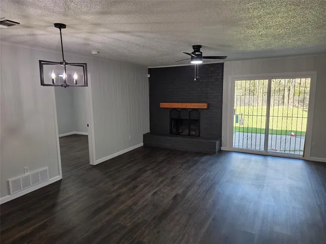 an empty room with wooden floor fireplace and chandelier
