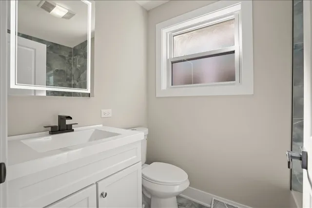 a bathroom with a toilet sink vanity and mirror