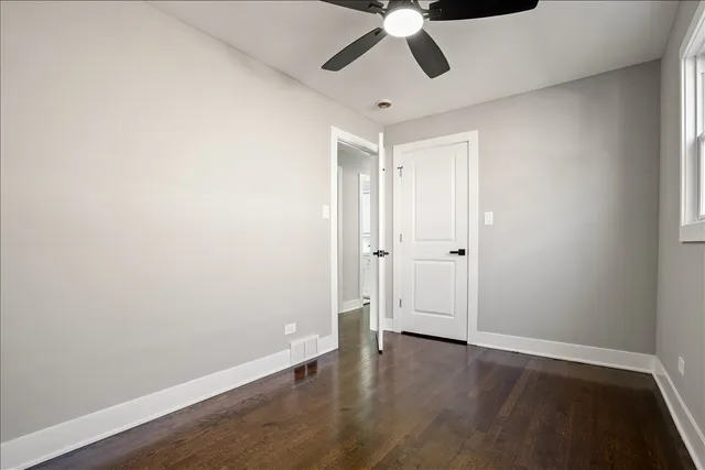 an empty room with wooden floor ceiling fan and window