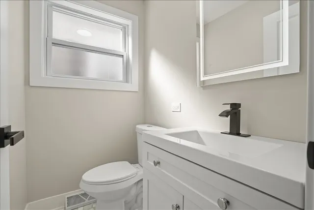 a bathroom with a toilet sink vanity and mirror
