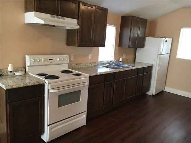 a kitchen with stainless steel appliances a sink a stove a refrigerator and cabinets