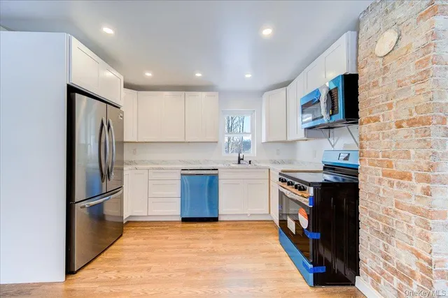 a kitchen with granite countertop a refrigerator stove top oven and sink