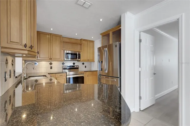 a kitchen with granite countertop stainless steel appliances a refrigerator a stove top oven and a sink