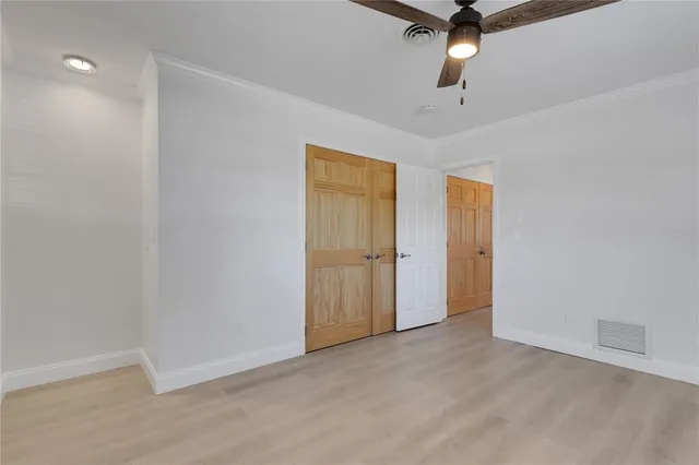 an empty room with closet and a chandelier fan