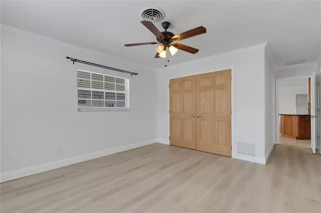 a view of empty room with wooden floor and ceiling fan
