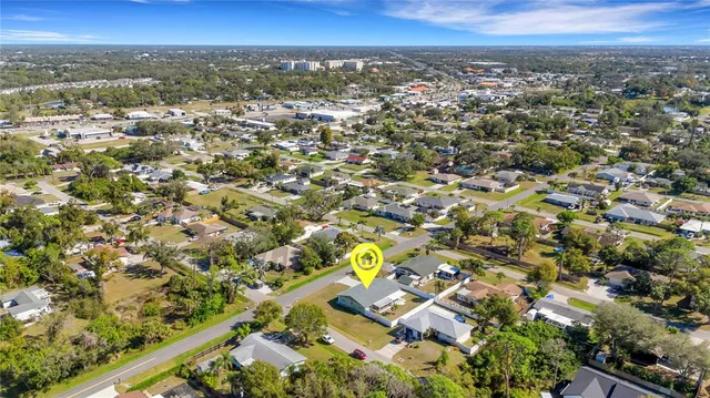 an aerial view of a house with swimming pool and large trees