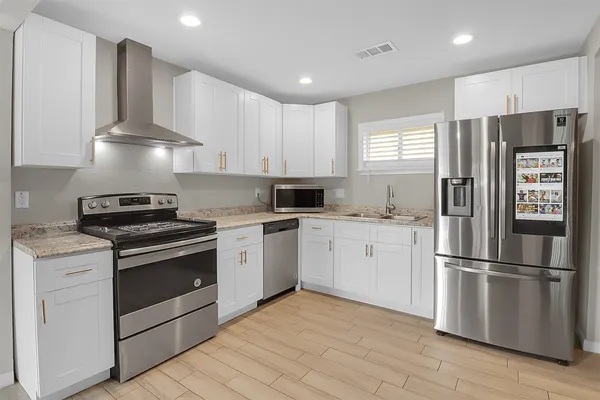 a kitchen with granite countertop a refrigerator stove top oven and sink