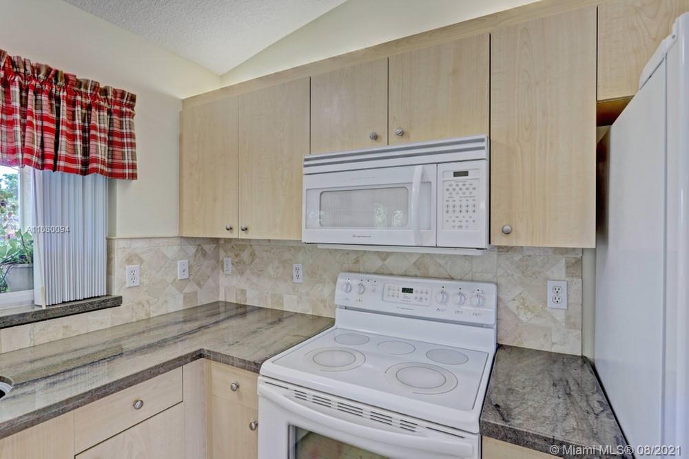 918 Southwest Longfellow Road, Unit 918 Port St. Lucie, FL 34953 - Photo 16 of 53 a kitchen with granite countertop cabinets and white appliances