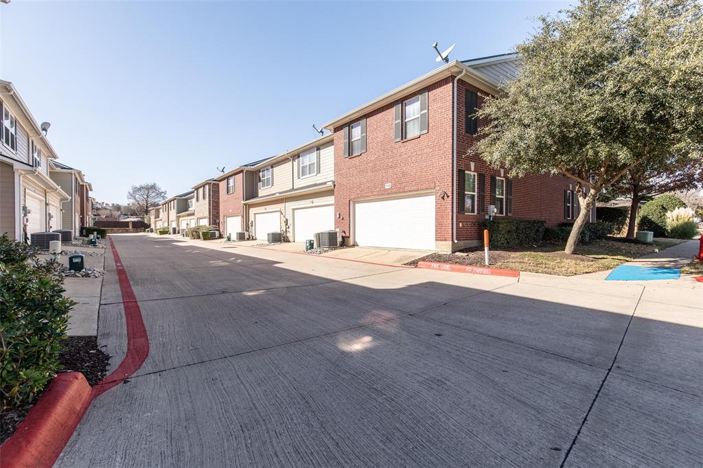 3118 Bedford Road Bedford, TX 76021 - Photo 29 of 29 Red brick and siding exterior townhouse featuring a white garage door, black window shutters, and established landscaping