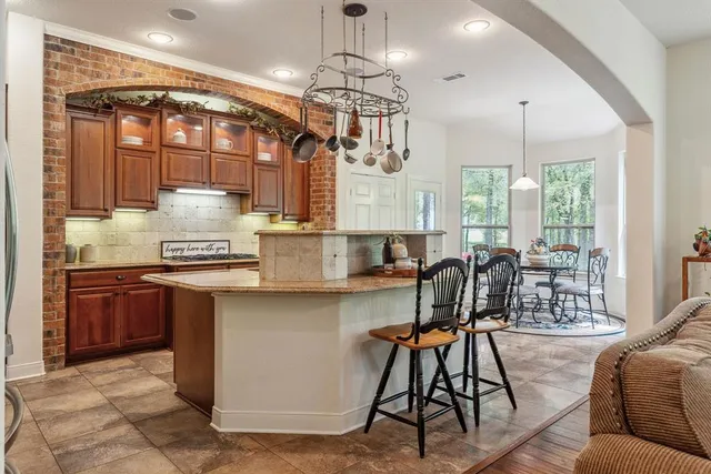 a kitchen with stainless steel appliances granite countertop a table chairs stove and wooden cabinets