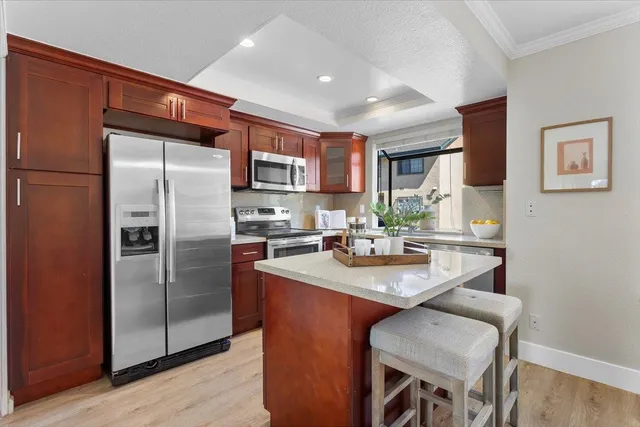 a kitchen with stainless steel appliances granite countertop a refrigerator a sink a stove a dining table and chairs