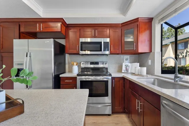 a kitchen with stainless steel appliances granite countertop a stove top oven a sink and a refrigerator
