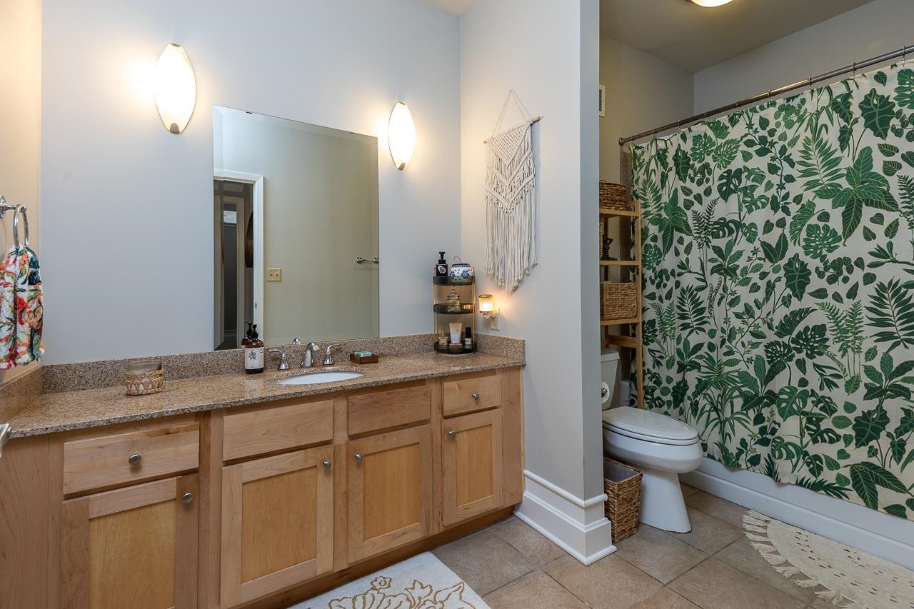 648 Riverside Drive, Unit 213 Memphis, TN 38103 - Photo 11 of 25 a bathroom with a granite countertop sink a toilet a mirror and shower curtain