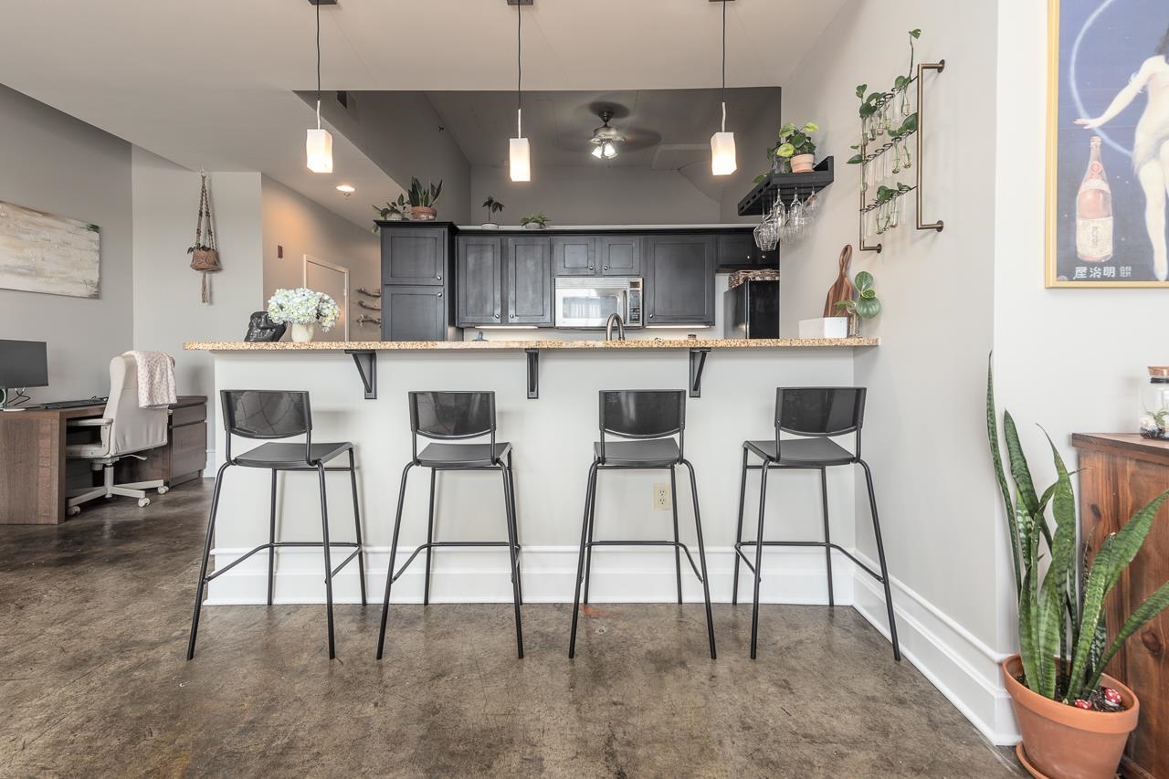648 Riverside Drive, Unit 213 Memphis, TN 38103 - Photo 6 of 25 a kitchen with stainless steel appliances kitchen island granite countertop a dining table chairs and a refrigerator
