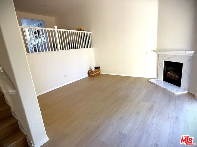 a view of an empty room with wooden floor and a fireplace